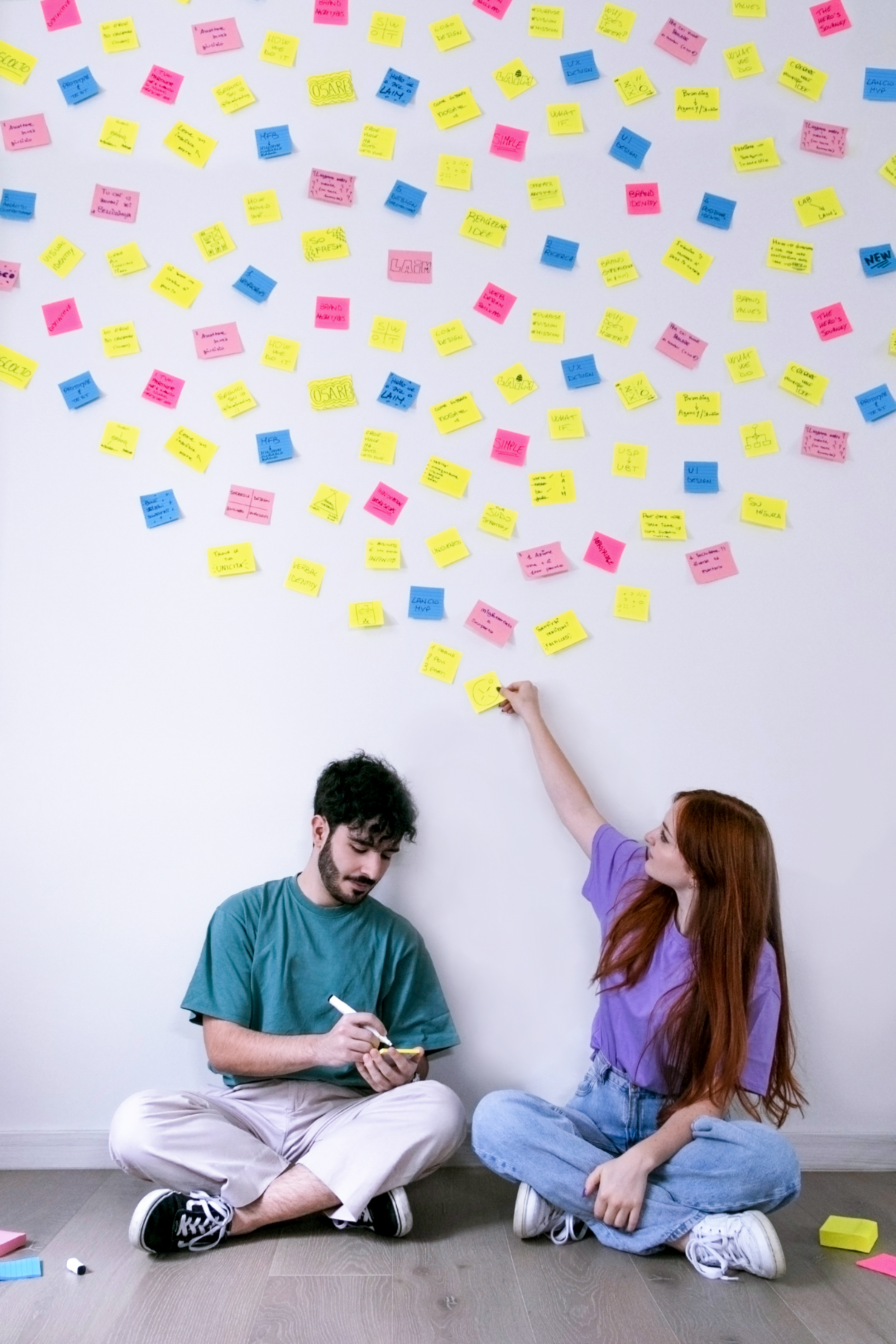 Noi due seduti con un muro pieno di post-it colorati dietro